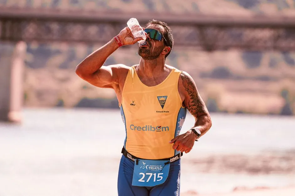 Coureur en tenue légère courant sous un soleil intense sur une route, gourde à la main